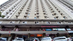 Un immeuble de grande hauteur doté de nombreux balcons et d’un espace commercial au rez-de-chaussée comprenant divers magasins.