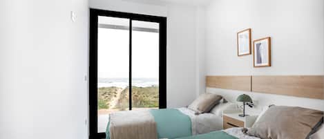 A bedroom with two beds, a nightstand, a lamp, and framed pictures on the wall.