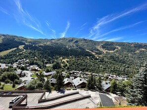 A residential area with houses, a parking lot, and a mountainous backdrop. - Functional Apt near slopes, shops, with balcony & WiFi in Méribel (Méribel)
