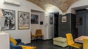 Una sala de estar moderna con un sofá azul, sillas amarillas, una mesa de comedor de madera y techo de ladrillo.