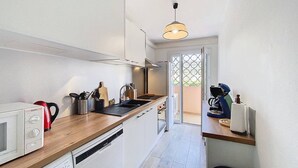 Eine moderne Küche mit weißen Schränken, einer Holz Arbeitsplatte, einer eingebauten Mikrowelle und einer Pendelleuchte.