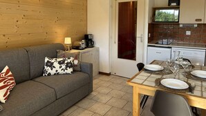 A cozy living room with a sofa, a coffee machine, and a dining table set for four.