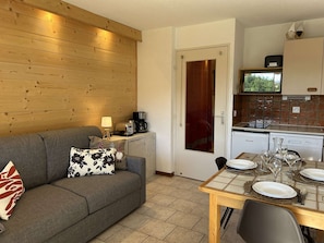 Una sala de estar acogedora con un sofá, una cafetera y una mesa de comedor para cuatro comensales.