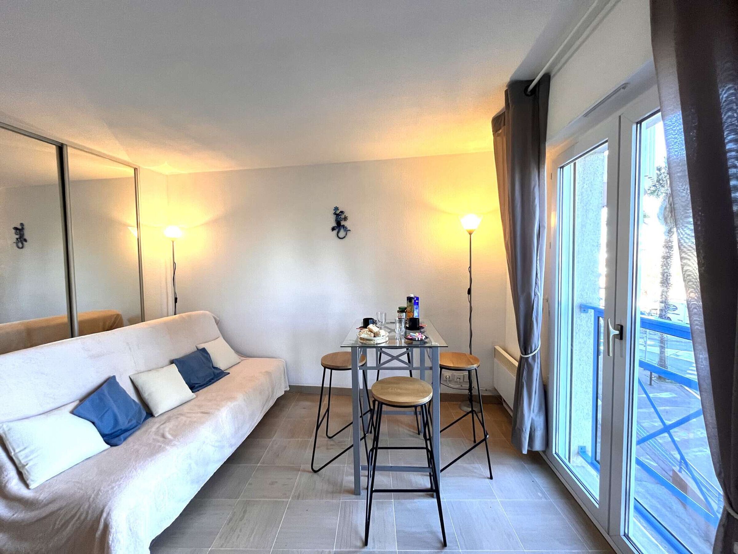Ett modernt hotellrum med en soffa, ett matbord med stolar och ett stort fönster med utsikt över omgivningarna.