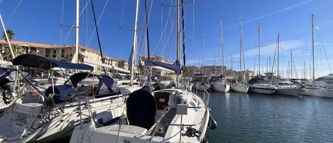 A marina with multiple sailboats docked, featuring a clear sky and calm water.