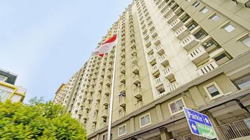 A high-rise building with multiple balconies and a flagpole with a flag.