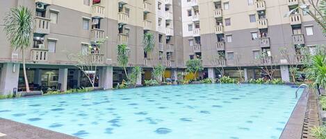 A swimming pool surrounded by a residential building with balconies.