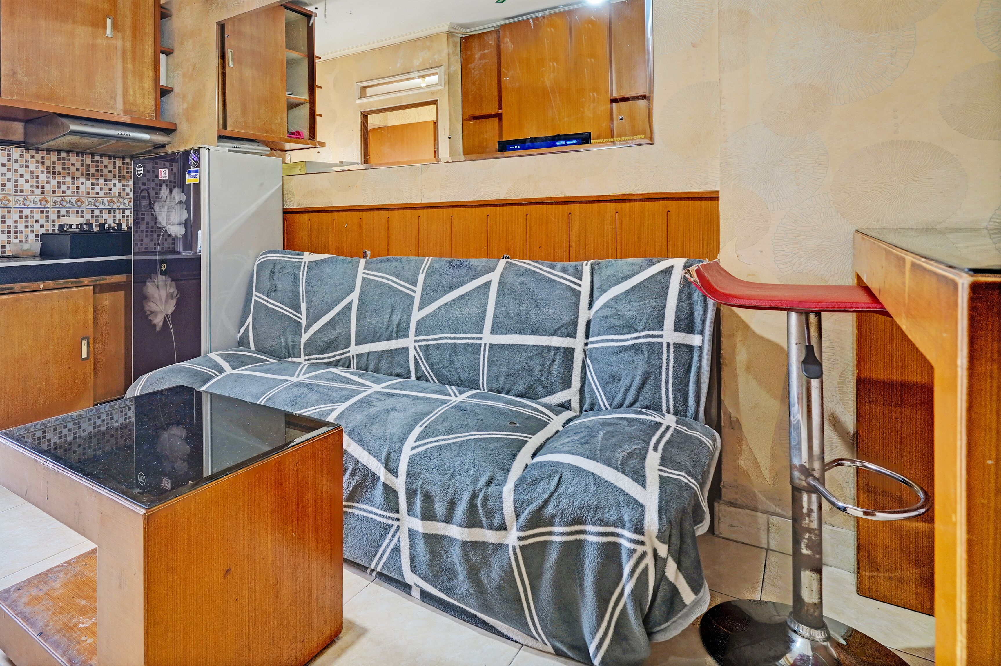 A compact kitchenette with a refrigerator, stove, and wooden cabinets.