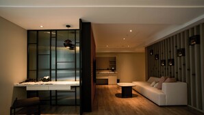 A modern living room with a sofa, a dining table, and a kitchen in the background. - XIUXI HOTEL (Tainan)
