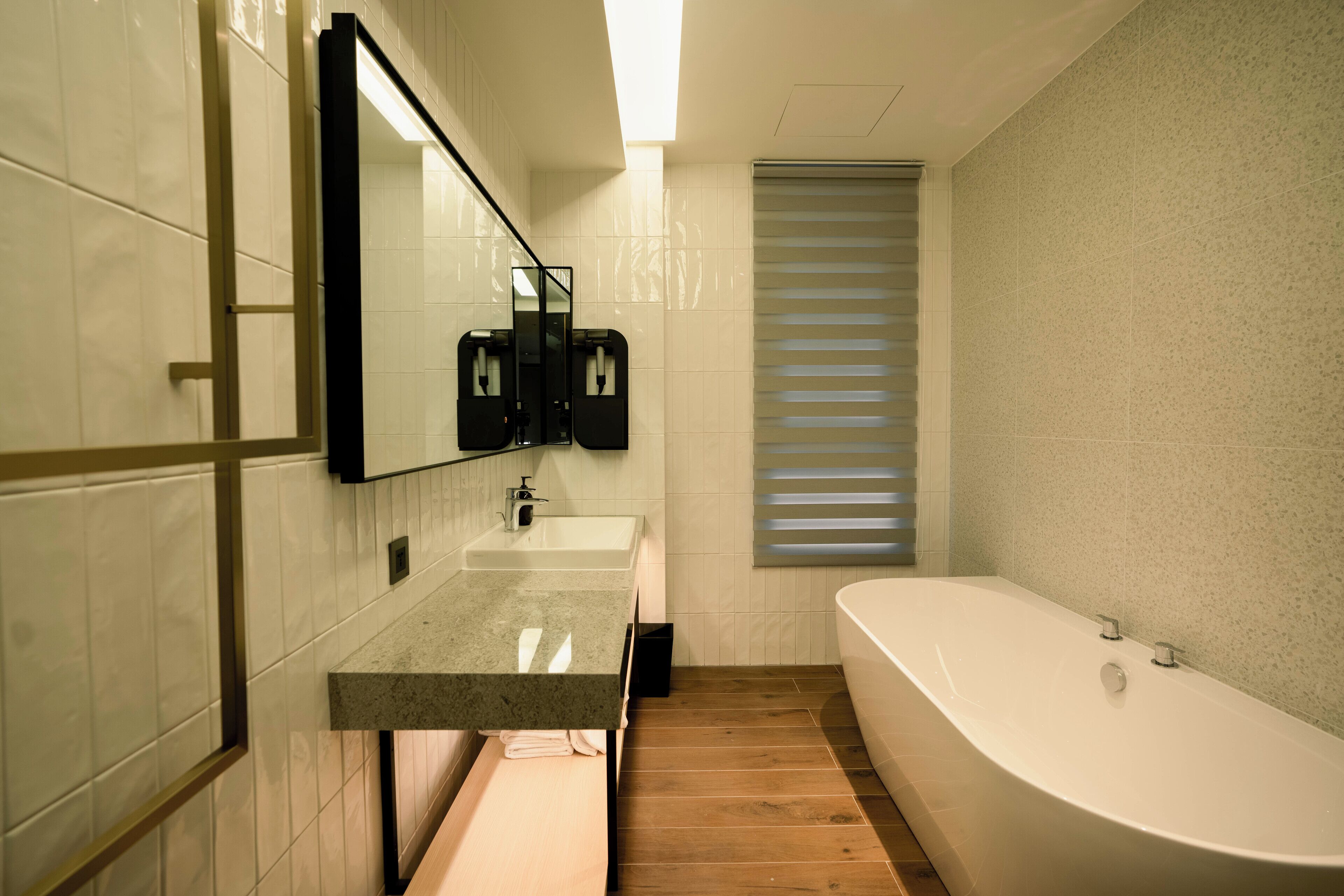 Un baño moderno con una bañera independiente, un espejo grande y un lavabo sobre encimera.