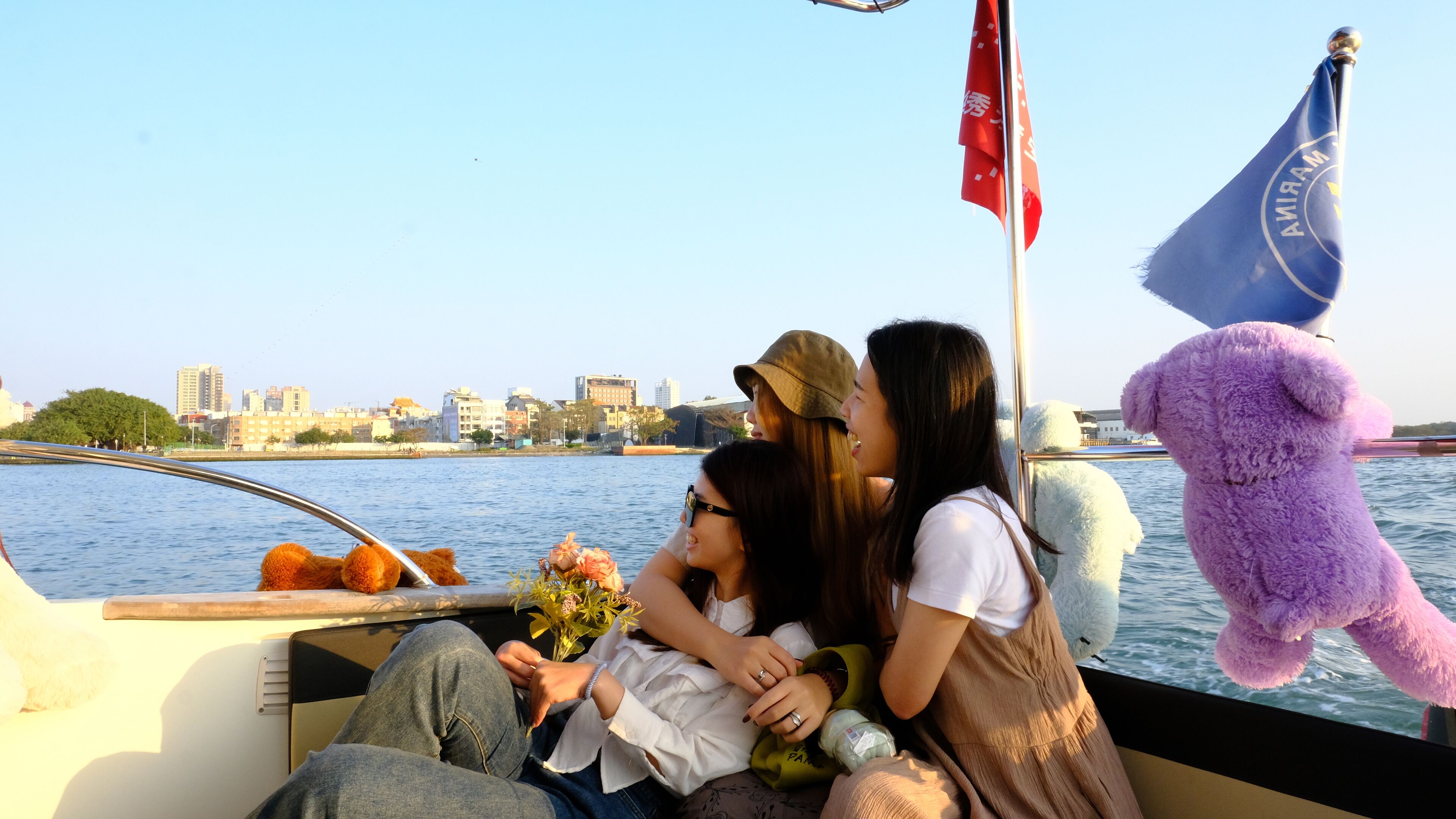 A boat with passengers, a city skyline in the background, and a flag.