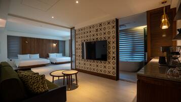 Una habitación de hotel moderna con cama, sofá y una pequeña mesa redonda.