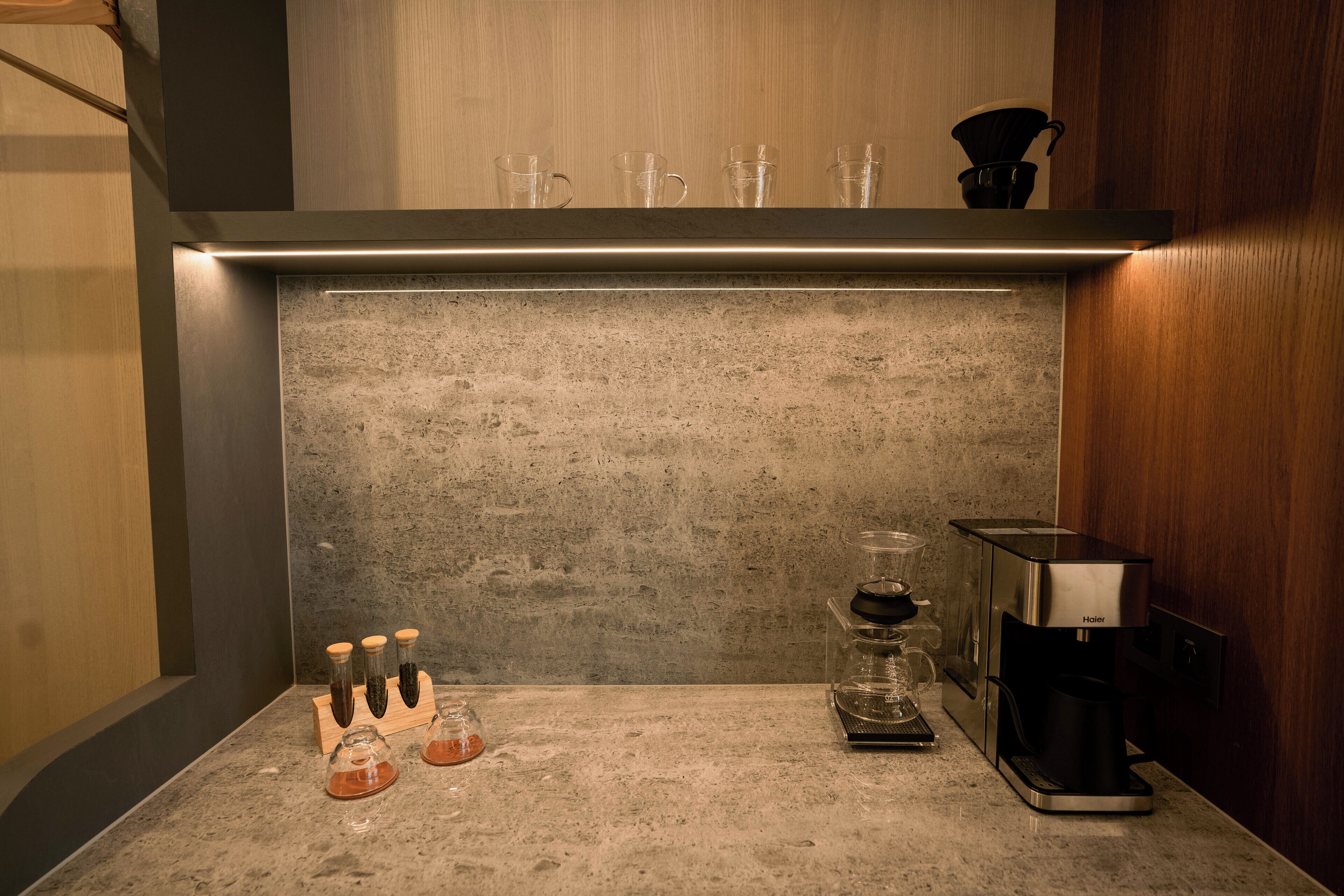 Una cocina con cafetera, recipientes de vidrio y una jarra de café sobre la encimera.