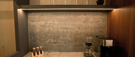 Una cocina con cafetera, recipientes de vidrio y una jarra de café sobre la encimera.
