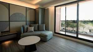 Uma sala de estar moderna com um sofá seccional, uma mesa de centro redonda e uma grande porta de vidro deslizante que dá para uma varanda.