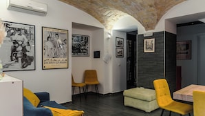 A modern living room with a blue sofa, yellow chairs, a wooden dining table, and a brick ceiling. - Cozy guesthouse in the center of Rome (Roma)