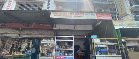 A street-side market with various stalls selling snacks, drinks, and household items.