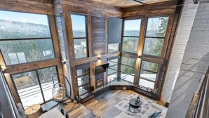 Un interior acogedor con chimenea, ventanas amplias y una zona de estar.