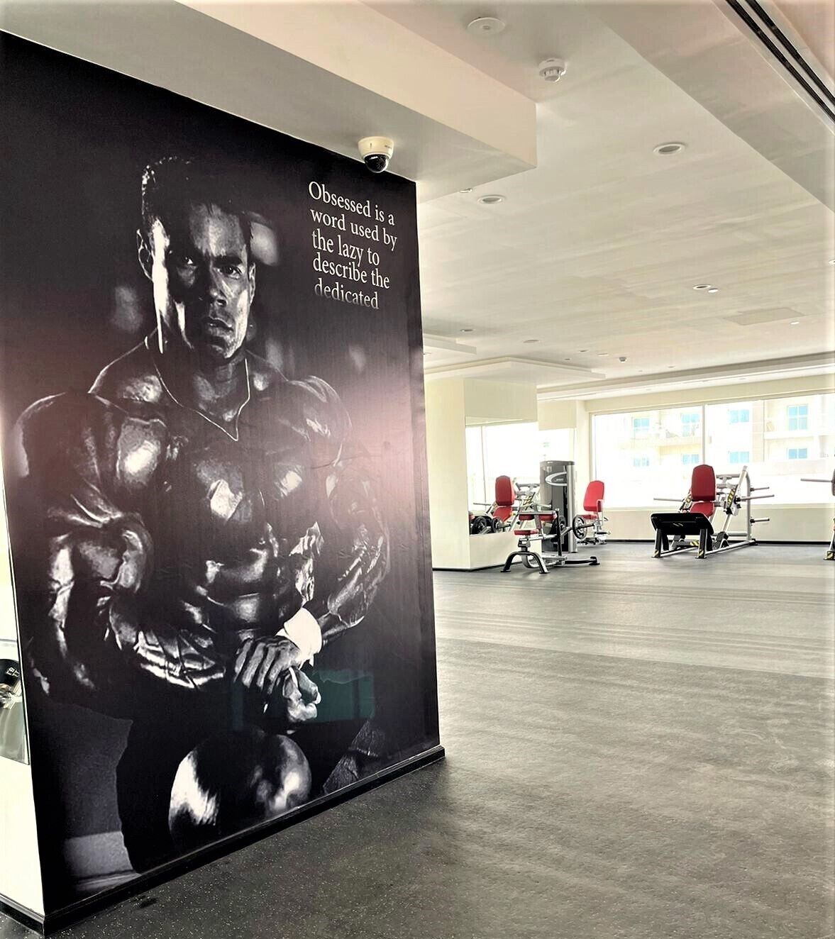 Une salle de sport équipée de matériel d’exercice et ornée d’une grande affiche représentant une silhouette musclée.