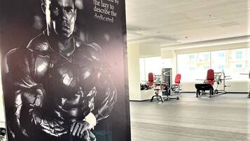 Une salle de sport équipée de matériel d’exercice et ornée d’une grande affiche représentant une silhouette musclée.