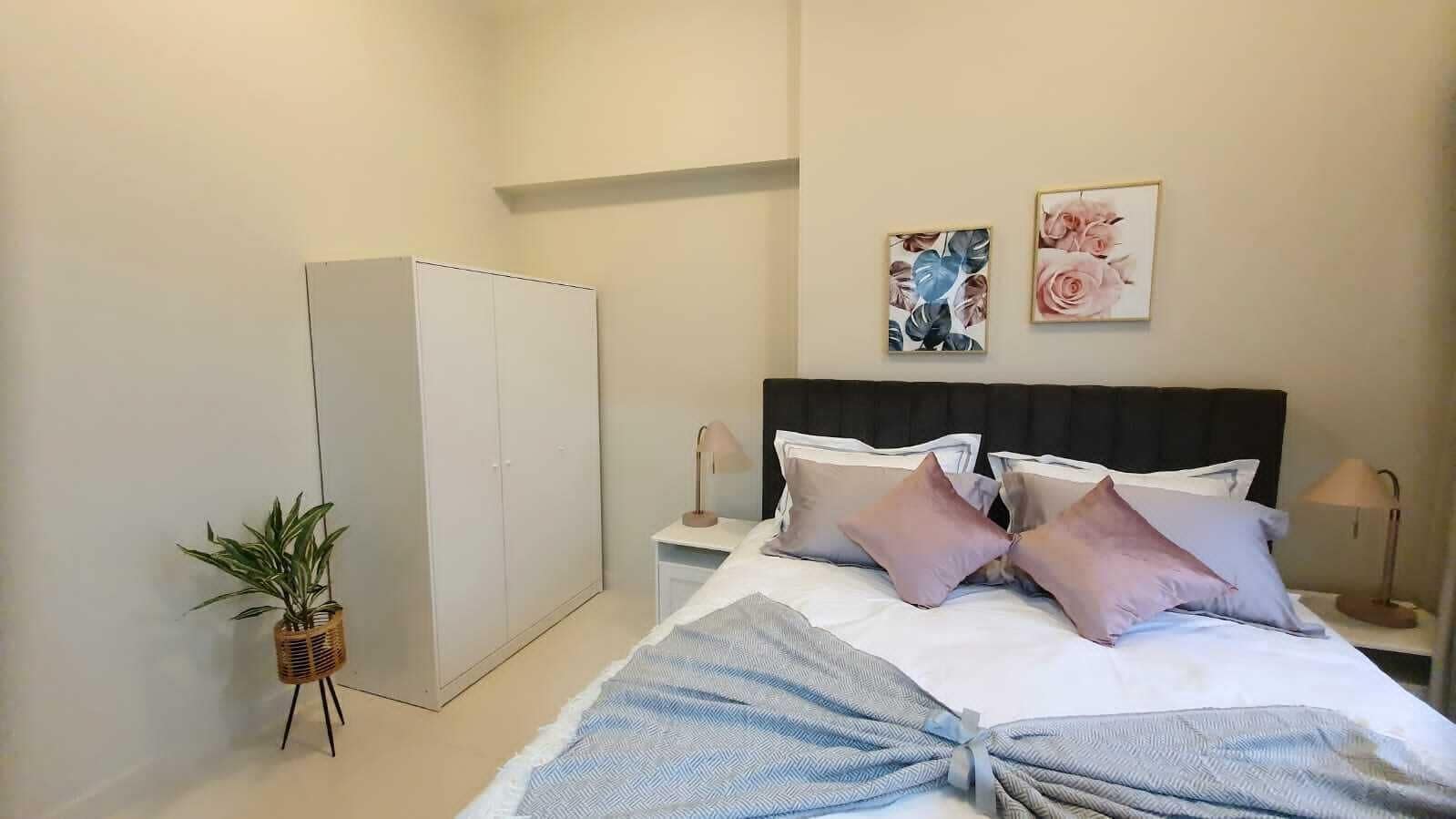 A bedroom with a bed, bedside tables, a wardrobe, and a potted plant.
