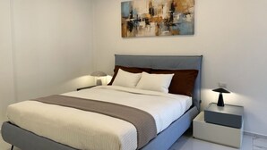 Ein modernes Schlafzimmer mit einem Bett, Nachttischen und einem Bild an der Wand.