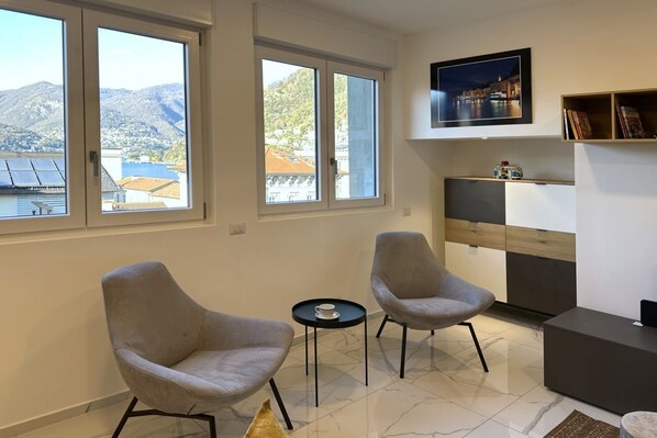 A modern living room with two armchairs, a small table, a flat-screen TV, and a bookshelf. - Dolce Vista Mantovani Palace (Como)