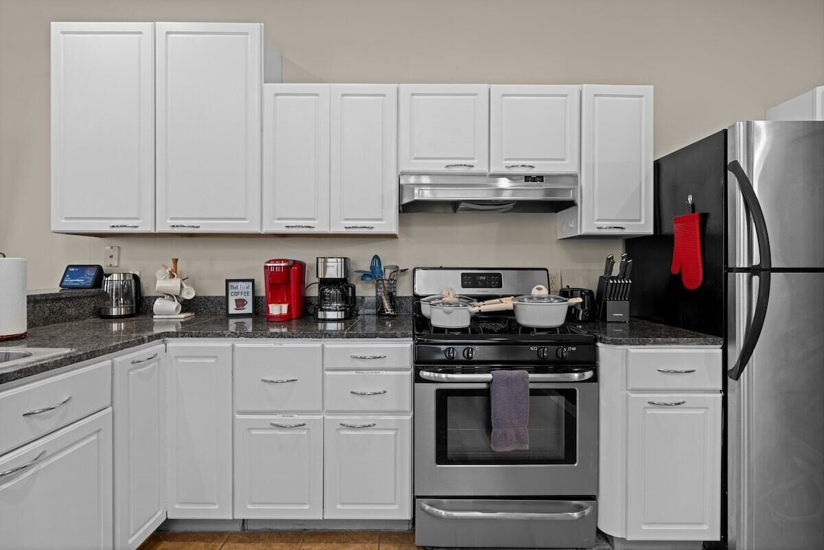 A modern kitchen with white cabinets, stainless steel appliances, and a granite countertop.