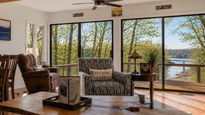 Ein Zimmer mit großem Fenster mit Seeblick, Deckenventilator und einem Schild mit der Aufschrift 'AM SEE GENIESSEN'.