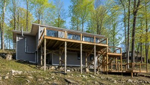 Eine zweistöckige Holzhütte mit einem Balkon, umgeben von Bäumen.