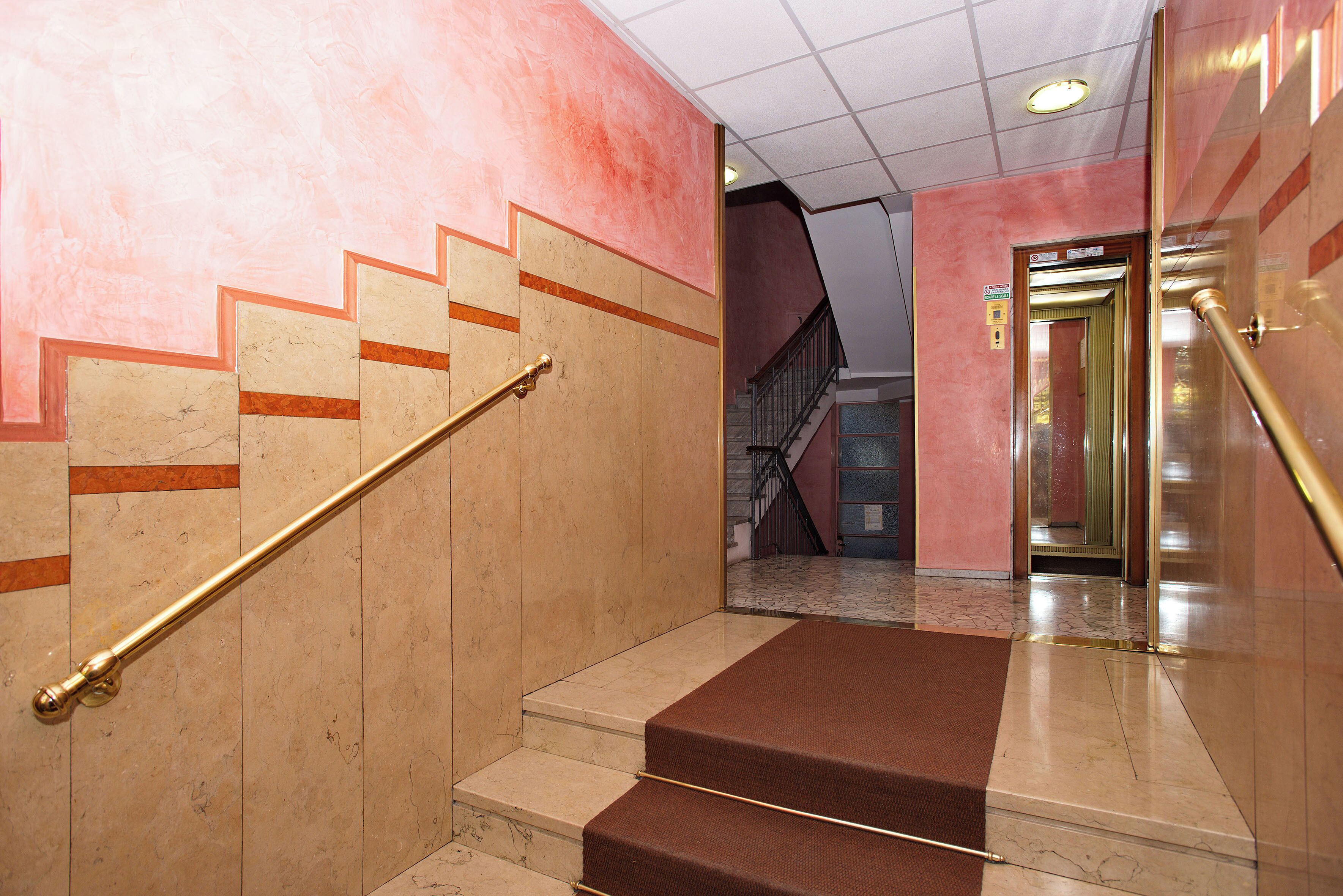 A marble staircase with a handrail, leading to an elevator.