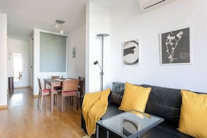 Ein modernes Wohnzimmer mit einer schwarzen Ledersofa, einem Glastisch und einem Essbereich mit Holzsesseln und einem Tisch.