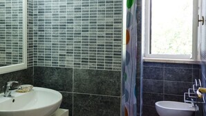 Une salle de bain avec un lavabo blanc, un miroir et une fenêtre.