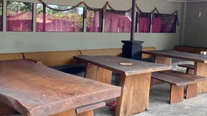 A room with wooden benches and tables, a sofa, and a trash bin. - Hotel O Gians Homestay Near SMKN 2 Kuripan (Janapria)