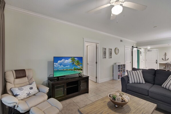 A living room with a TV, a reclining chair, a sofa, and a coffee table. - Beachfront Waterscape Condo, 2 King Suites, Bunk Room and Pools (Fort Walton Beach)