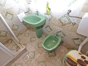 A bathroom with a green sink, a bidet, and a toilet.