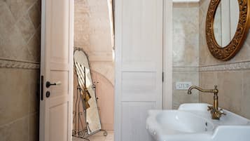 Un baño con un lavamanos blanco, un grifo dorado y un espejo con un marco ornamentado.