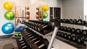 Une salle de sport équipée de matériel d’exercice, notamment des haltères et des ballons de gymnastique.