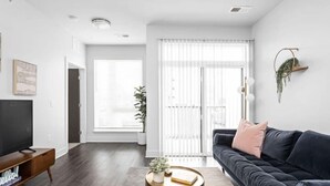 Un salon moderne avec un canapé foncé, une table basse ronde et un téléviseur posé sur un meuble en bois.