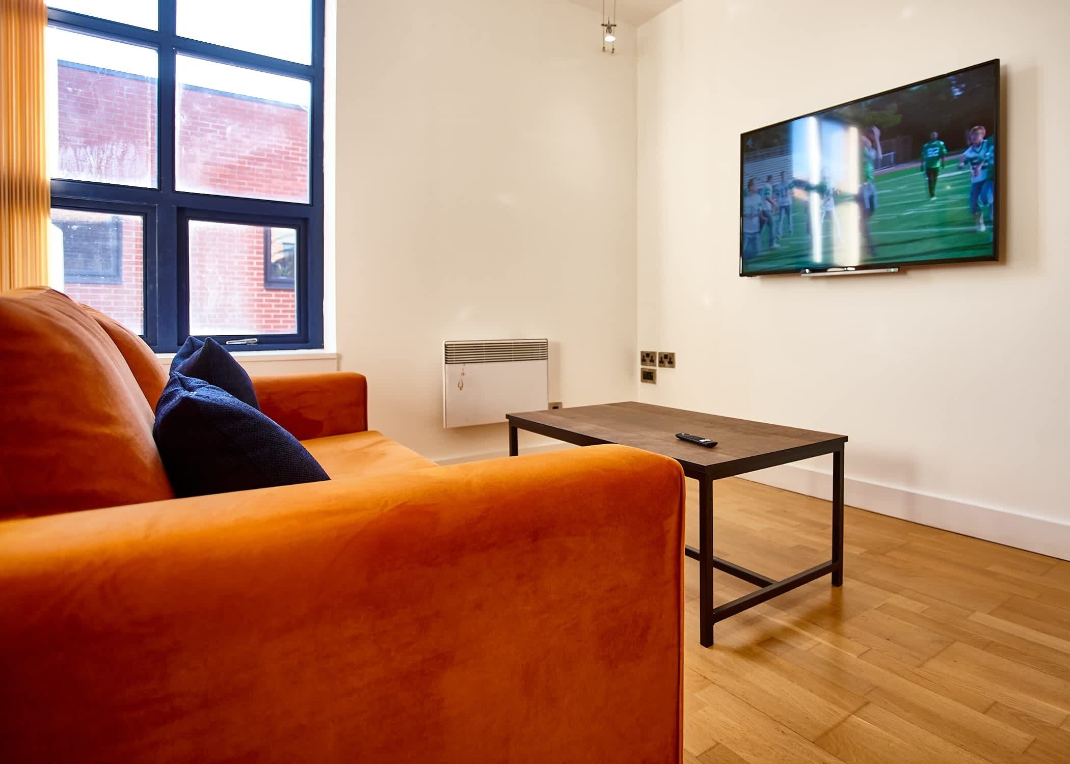 Un soggiorno moderno con un divano, un tavolino da caffè e una TV a parete.