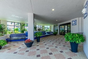 A covered outdoor area with a tiled floor, benches, potted plants, and a view of the outside. - Beachfront 3BR condo with pool, wifi, and Marco Island views. (Marco Island)