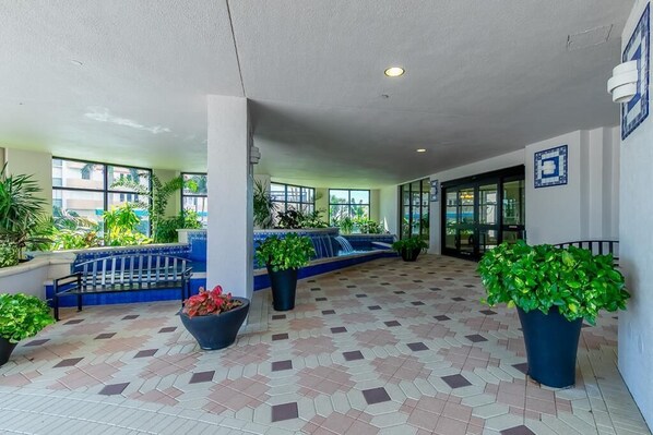 A covered outdoor area with a tiled floor, benches, potted plants, and a view of the outside. - Beachfront 3BR condo with pool, wifi, and Marco Island views. (Marco Island)