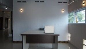 A modern hotel room with a minimalist design, featuring a large window, a desk with a laptop, and built-in lighting.