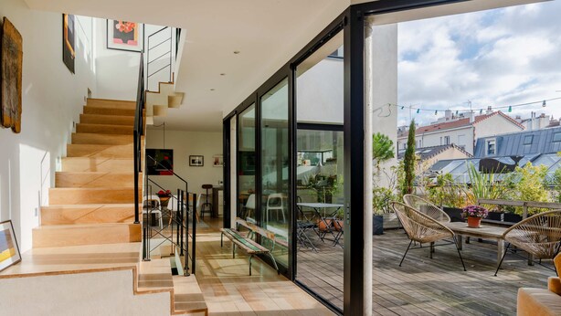 A modern interior with a wooden staircase leading to a glass door opening to an outdoor deck. - Paris Mimosa Penthouse Residences (Boulogne-Billancourt)
