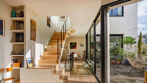 A modern interior with a staircase leading to a balcony, wooden flooring, and a view of the outside. - Paris Mimosa Penthouse Residences (Boulogne-Billancourt)