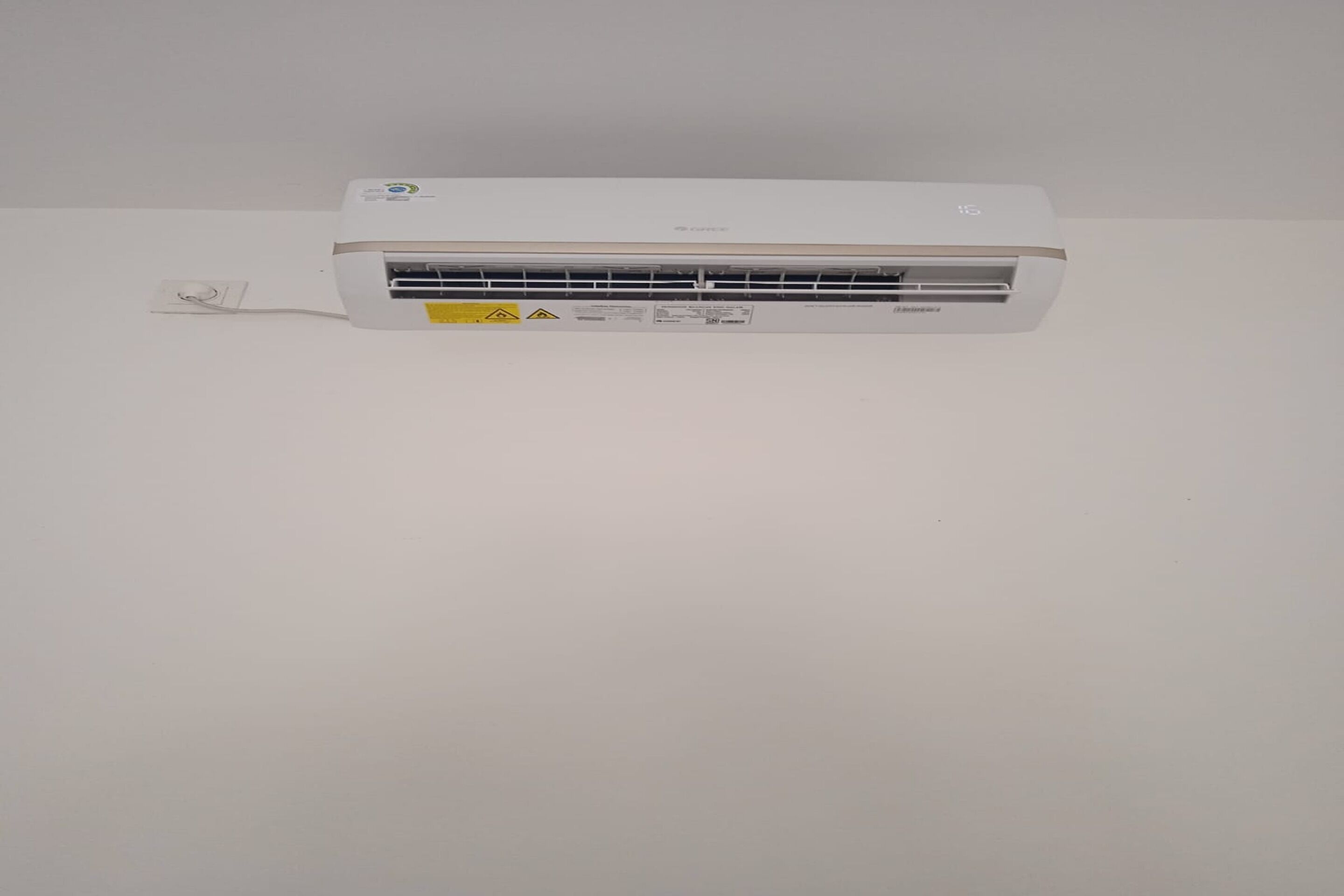 A white wall-mounted air conditioner with a control panel and a warning label.