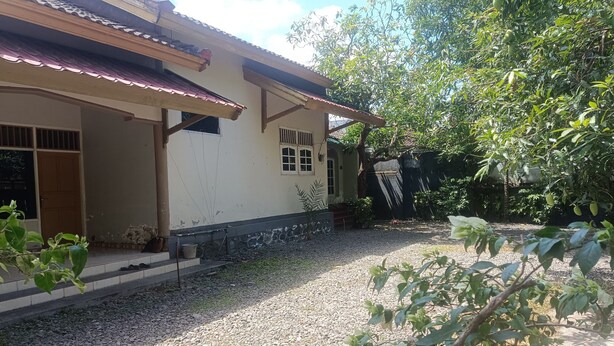 Ein Haus mit einem Ziegeldach, einer Veranda und einer Auffahrt mit Kies.