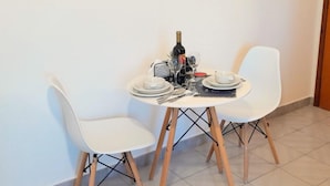 A dining table with two white chairs, a bottle of wine, and a small bowl. - IQ Malamo Studios Lambi Beach  (Kos)