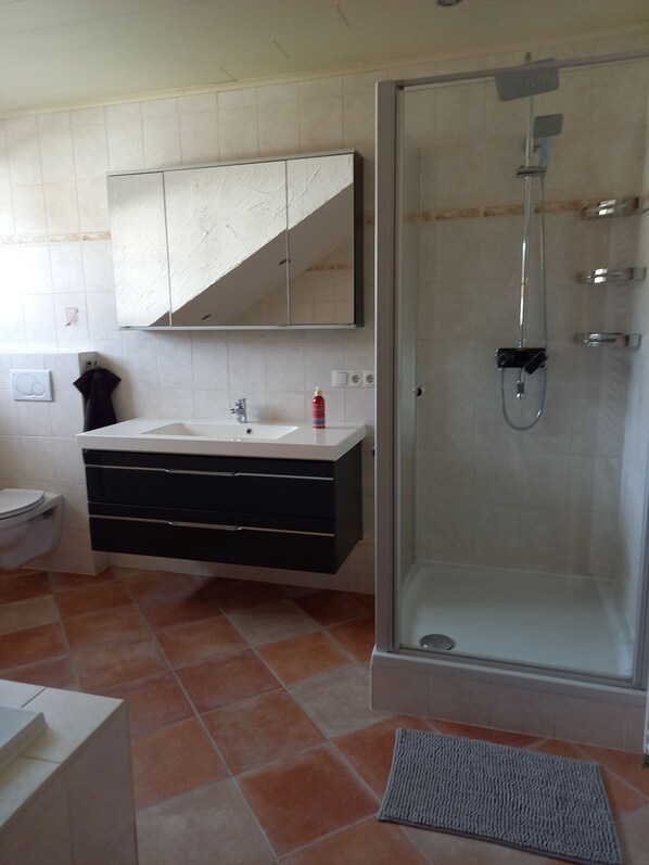 A bathroom with a glass-enclosed shower, a white sink with a black cabinet, and a mirror above the sink.