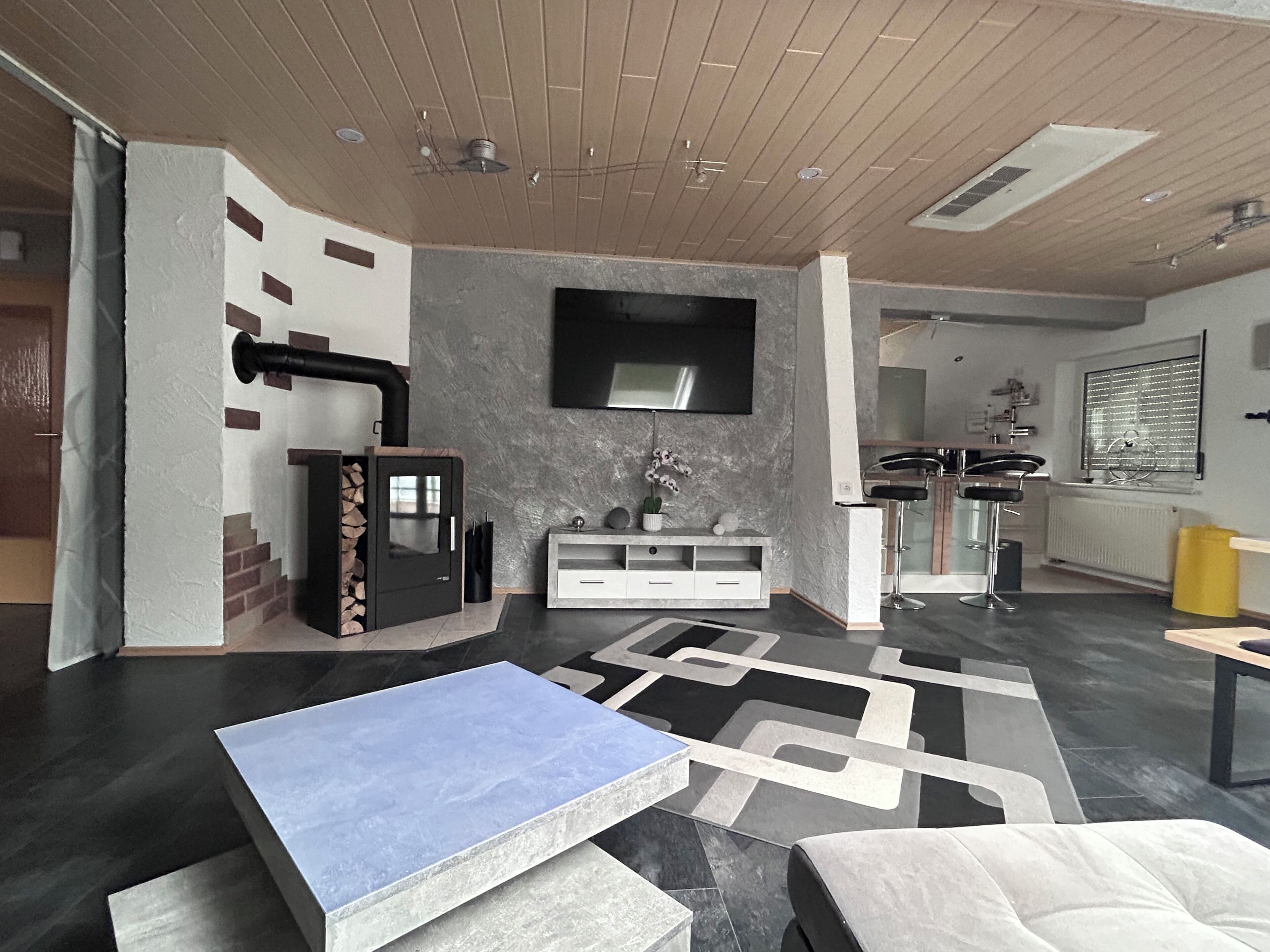 A modern living room with a fireplace, a flat-screen TV, and a dining area with a bar.